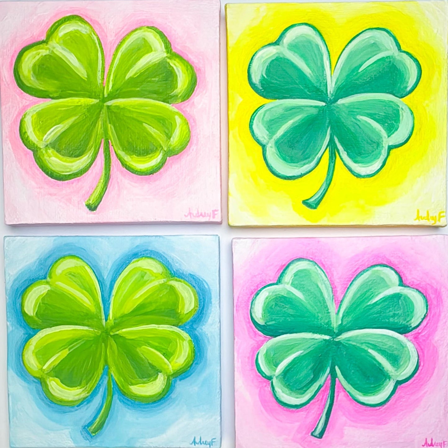 Four paintings of green four-leaf clovers on colorful backgrounds