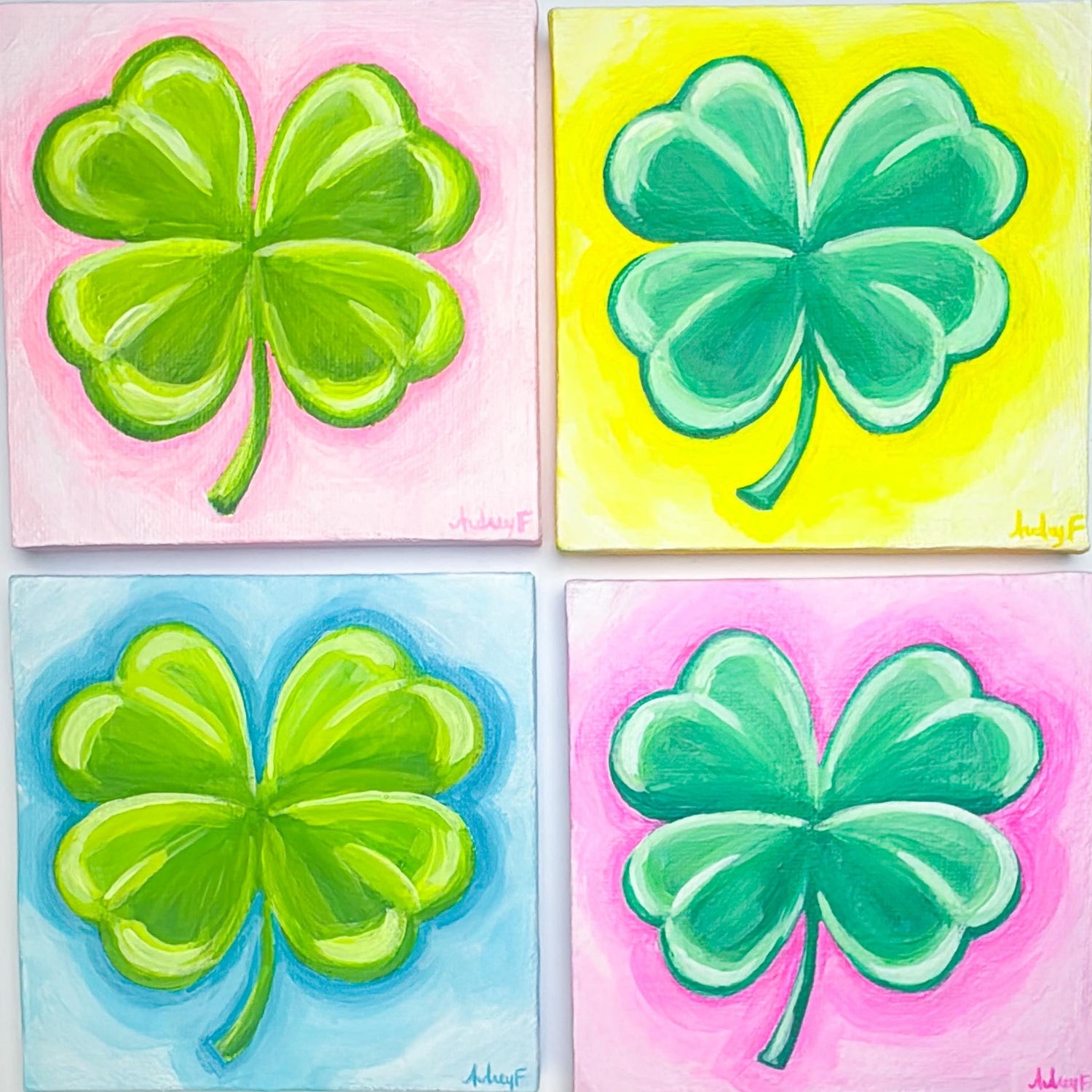 Four paintings of green four-leaf clovers on colorful backgrounds
